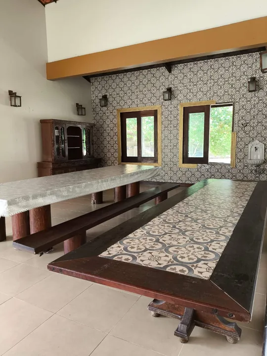 Mesas compridas com bancos e parede decorada na área de jantar.