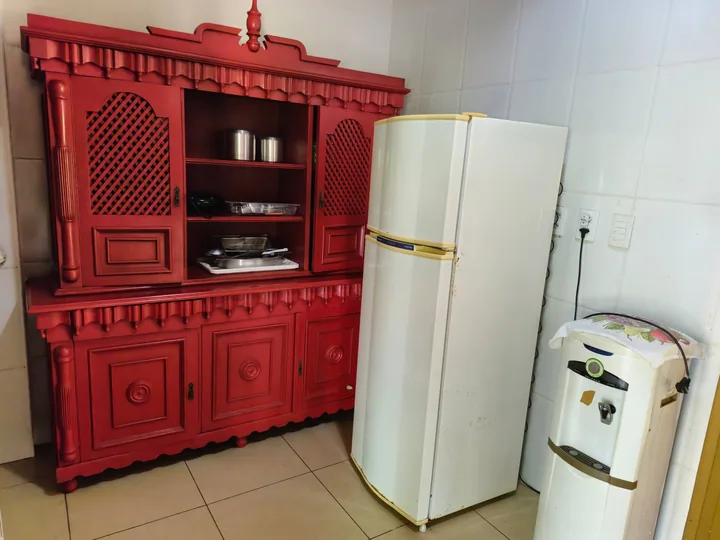 Armário vermelho, geladeira e bebedouro na cozinha completa.