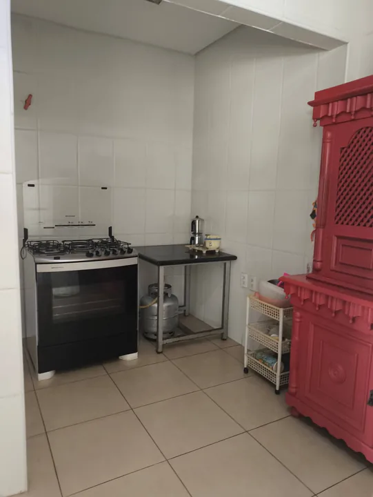 Fogão, bancada de apoio e armário vermelho na cozinha.