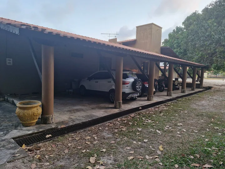 Garagem coberta com carros estacionados ao lado da casa.