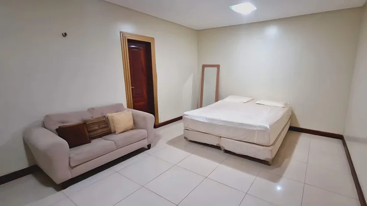 Quarto 1 com cama de casal e sofá claro.