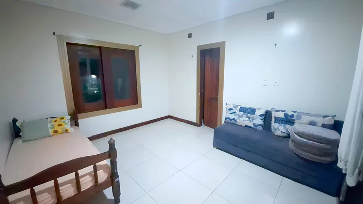 Quarto 3 com cama, sofá azul e janela de madeira.