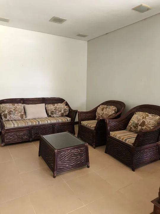 Sala de estar com sofá, duas poltronas de fibra e mesa de centro.
